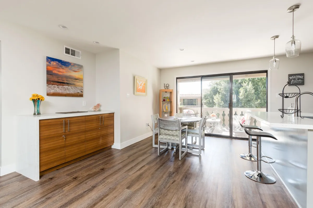 A welcoming dining area adjoining the kitchen, featuring a dining table, stylish kitchen island, wall art, and large windows. The space is arranged for gatherings, whether casual or festive.