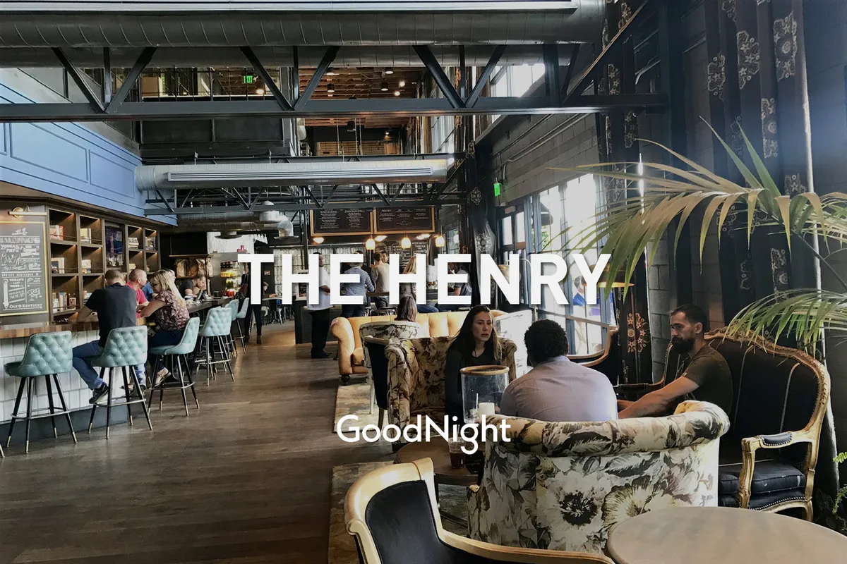 An inviting indoor bar area with stylish seating arrangements, decorative plants, and people engaged in socializing and dining. The atmosphere is lively and modern, reflecting a sense of community and shared enjoyment.
